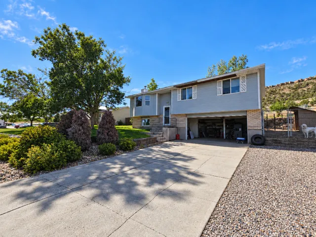 Split-level residence featuring a concrete driveway, attached garage, and a retaining wall with integrated landscaping