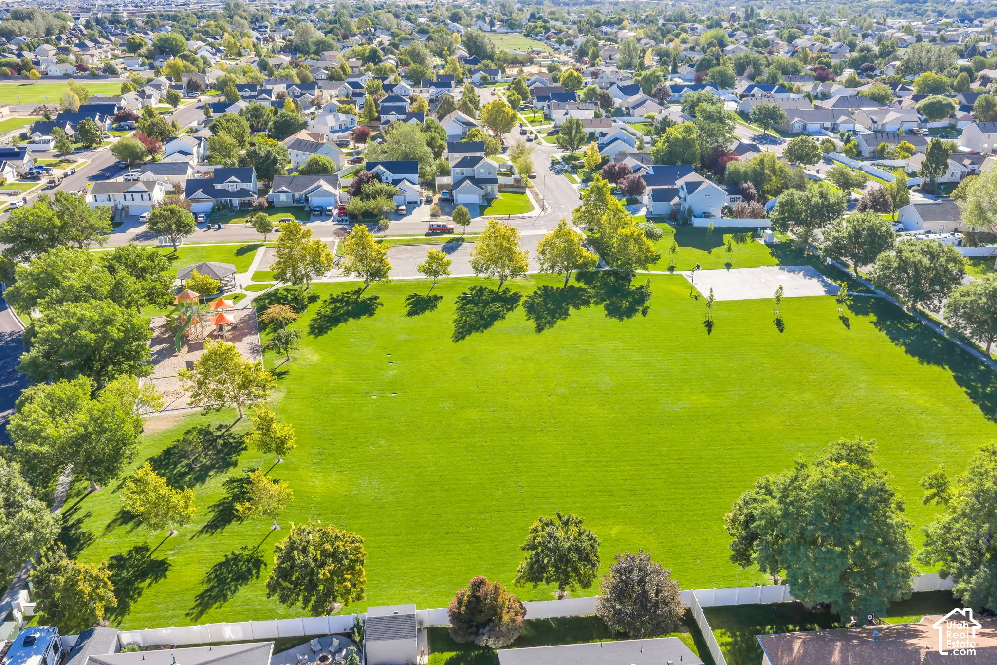 Beautiful neighborhood park with playground, mature trees, paved pathways, and a sports court