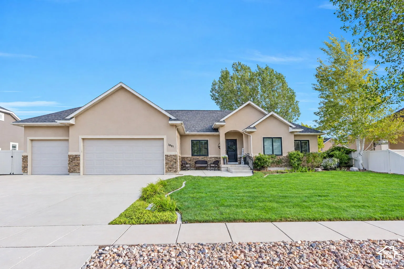 Stucco exterior with stone accents, covered entry, and a three-car garage