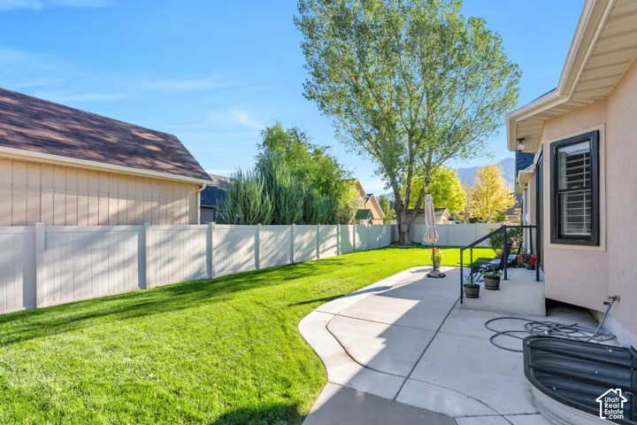 Expansive backyard with a manicured lawn, concrete patio, and a privacy fence