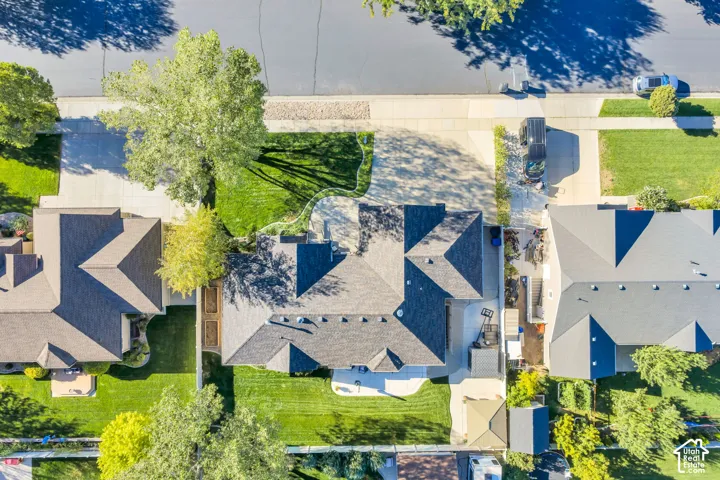 Expansive lot featuring a large driveway, established trees, mature landscaping, and an asphalt shingle roof