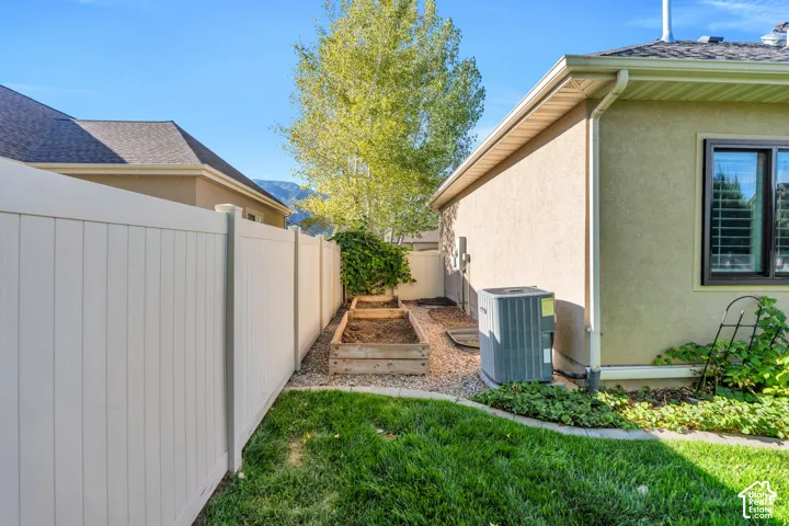 Manicured lawn with white privacy fencing, raised garden beds, and gravel landscaping