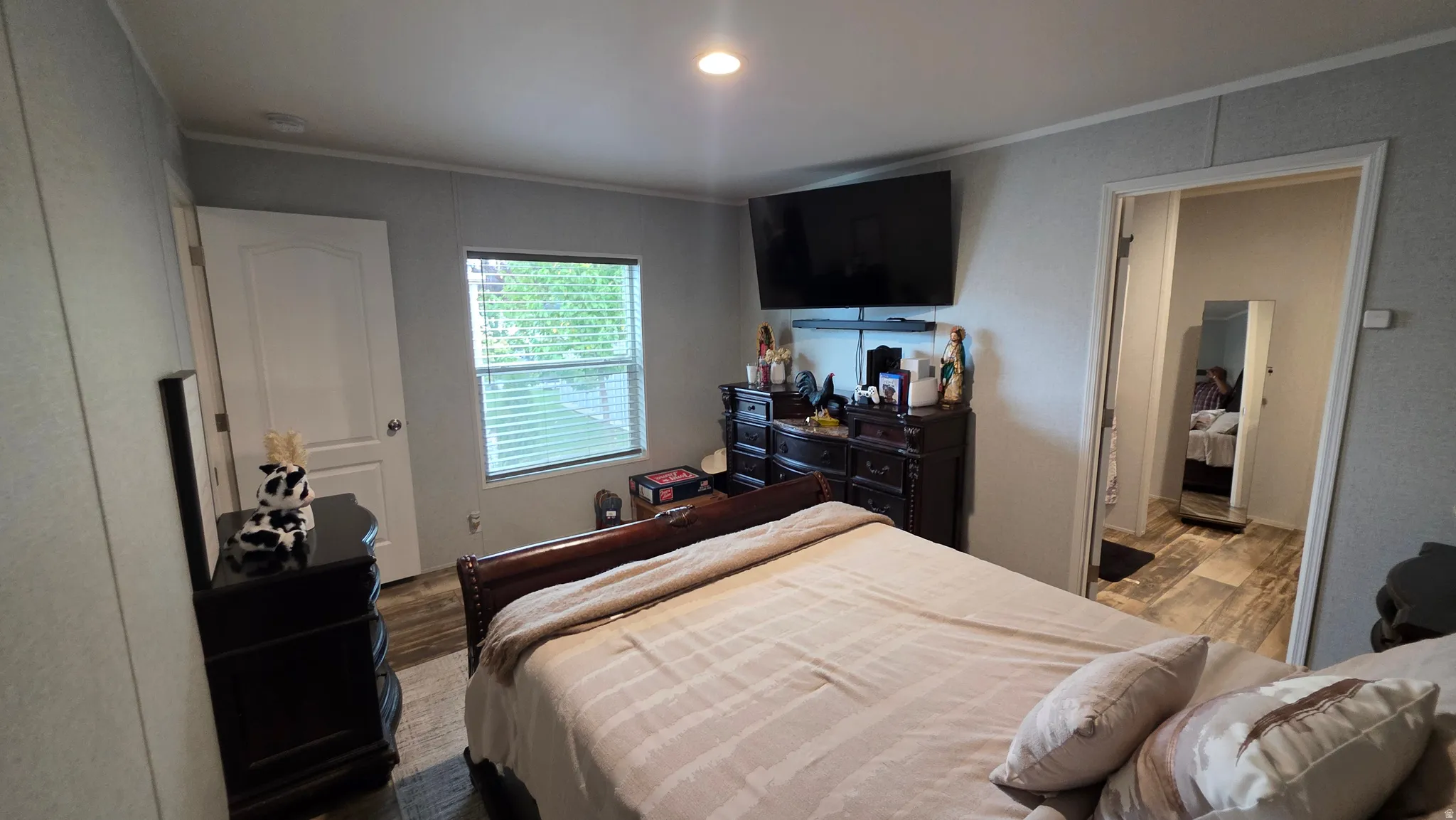 Recessed ceiling light, window with blinds, wood-finish flooring, and white interior doors