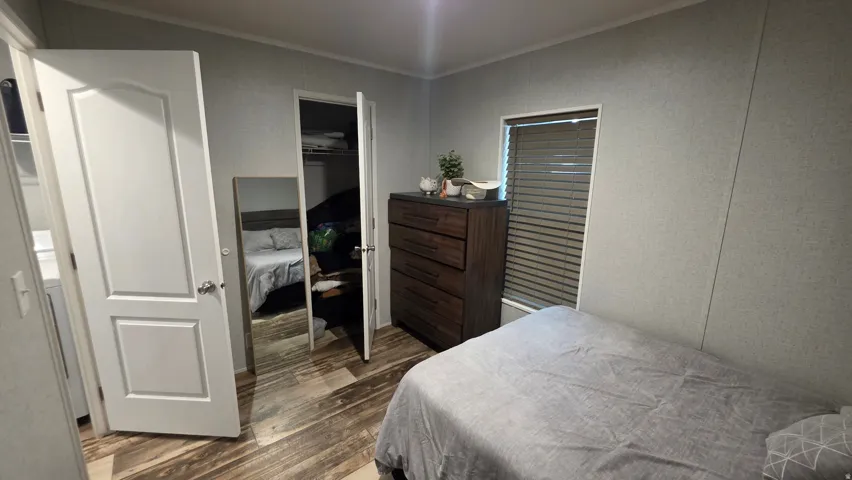 Wood-finish flooring, white paneled door, window with blinds, and built-in closet