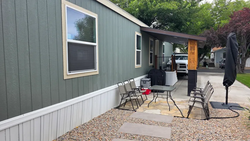 Gravel yard with stone pavers and a covered patio featuring a wood-wrapped support column