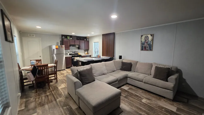Open-concept living area featuring wood-finish flooring, recessed lighting, and a kitchen with stainless steel appliances