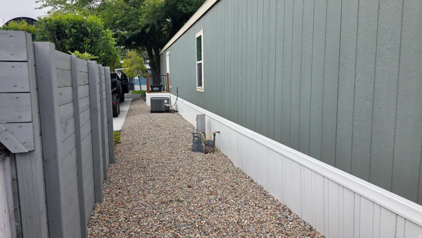Gravel side yard with a full-height privacy fence and board-and-batten style siding