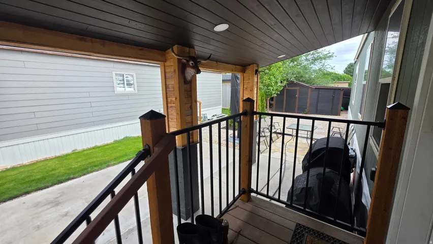Covered porch with wood-finish ceiling, wooden support beams, and metal railings