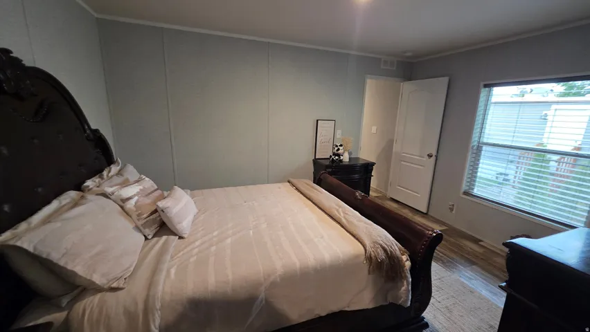 Wood-finish flooring, paneled wall finish, and a window with horizontal blinds