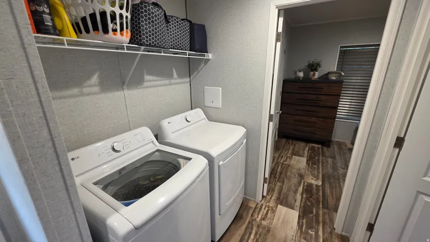 Laundry area featuring a wire shelving unit, wood-finish flooring, and light-toned wall covering