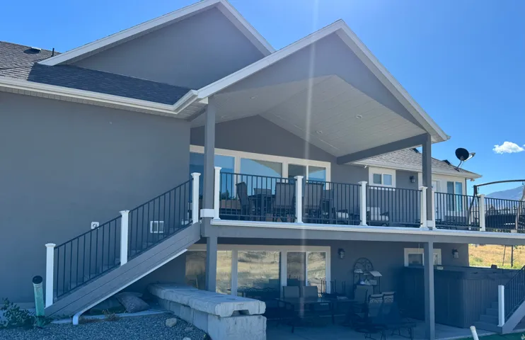 Multi-level outdoor living spaces featuring a covered patio, covered deck, white railing, and exterior stairs