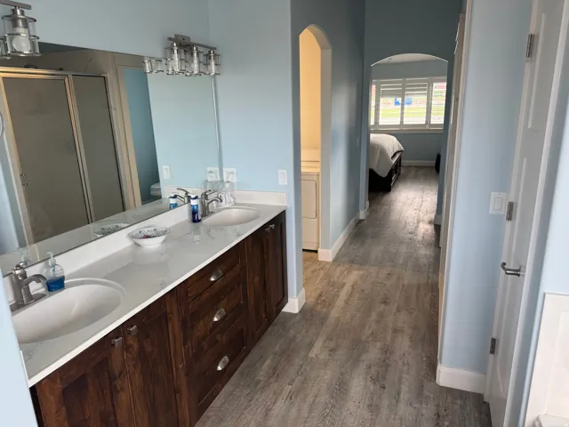 Dual vanity with undermount sinks, white countertop, cabinetry, and brushed nickel fixtures
