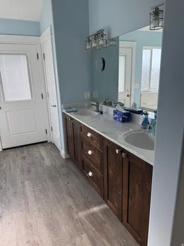 Dual vanity with dark wood-finish cabinetry, integrated sinks, and polished chrome hardware