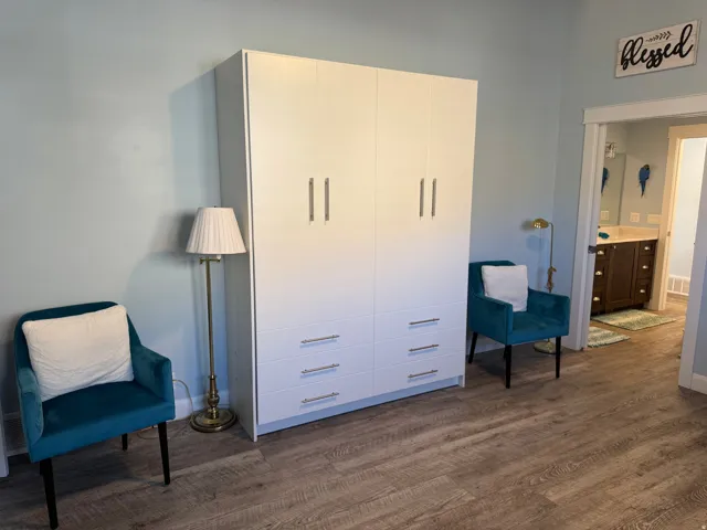 Vinyl flooring, white built-in murphy bed with brushed nickel hardware, and light blue wall color