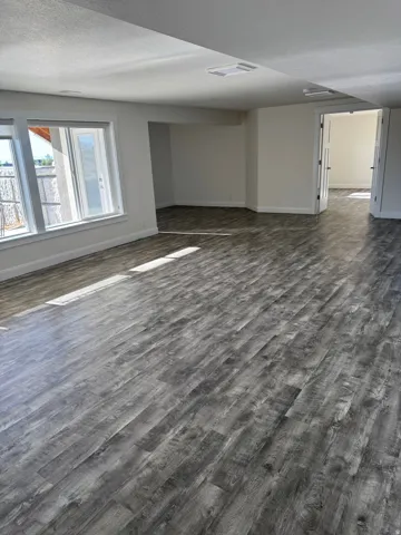 Spacious room with Vinyl flooring, white walls, multiple windows, and recessed lighting