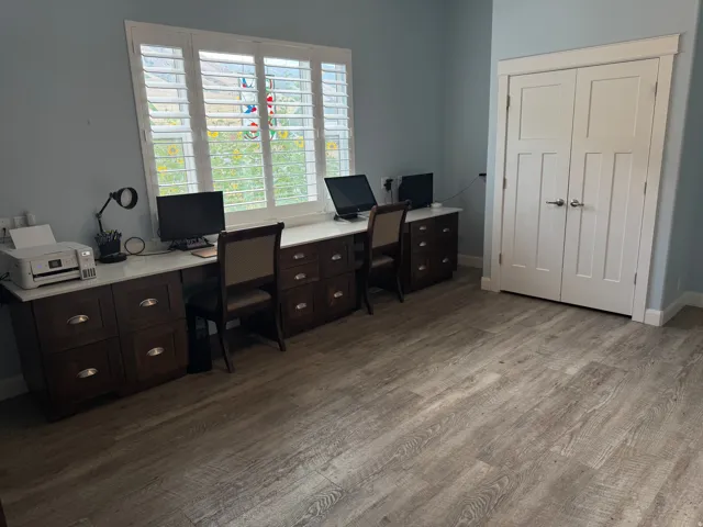 Vinyl flooring, plantation shutters, built-in desk cabinetry with nice countertops, and double panel closet doors