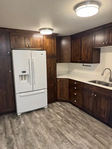 Vinyl flooring, dark wood cabinetry, white countertops, double basin sink, and ceiling-mounted flush lighting