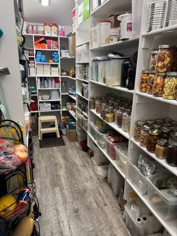 Organized pantry featuring extensive built-in shelving with multiple tiers, ample storage for dry goods and pantry staples, Vinyl flooring, and efficient layout maximizing storage capacity throughout
