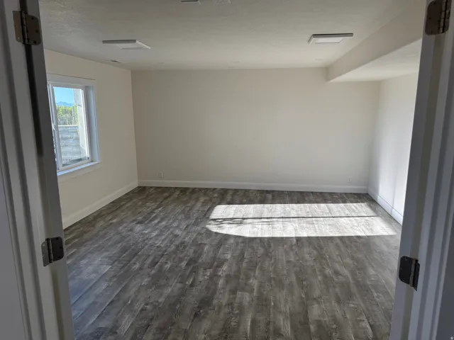 Spacious room featuring Vinyl flooring, white walls, and a window