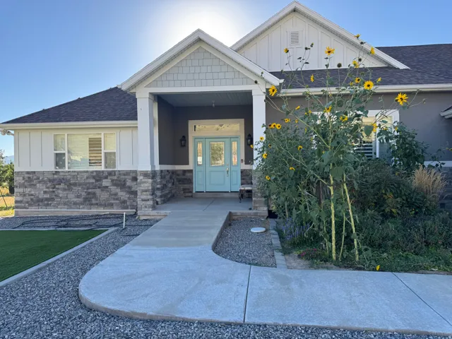 Stucco exterior with stone veneer accents, covered porch entrance, and a light blue double-door entry