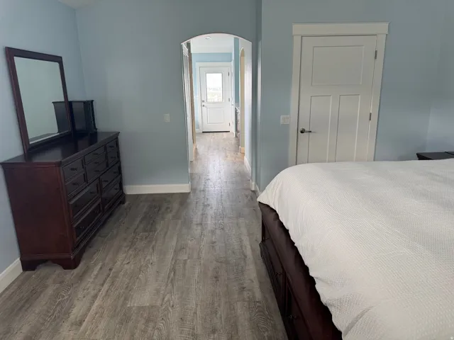 Vinyl flooring throughout, framed arched doorway, and a paneled white interior door