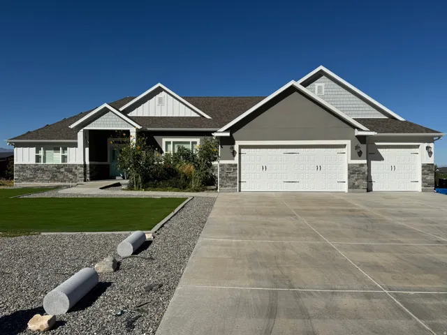 Contemporary residence featuring a multi-tone exterior, attached three-car garage, concrete driveway, and front landscaping with artificial turf and gravel