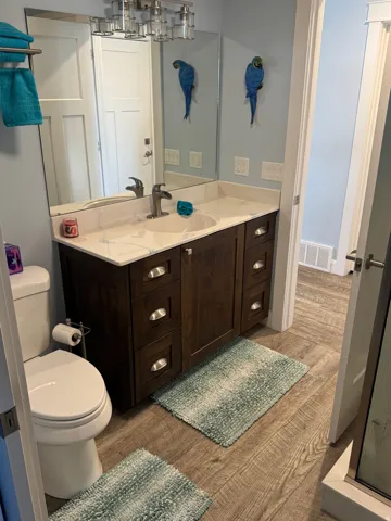 Vinyl flooring with a dark wood vanity, white countertop, and integrated sink