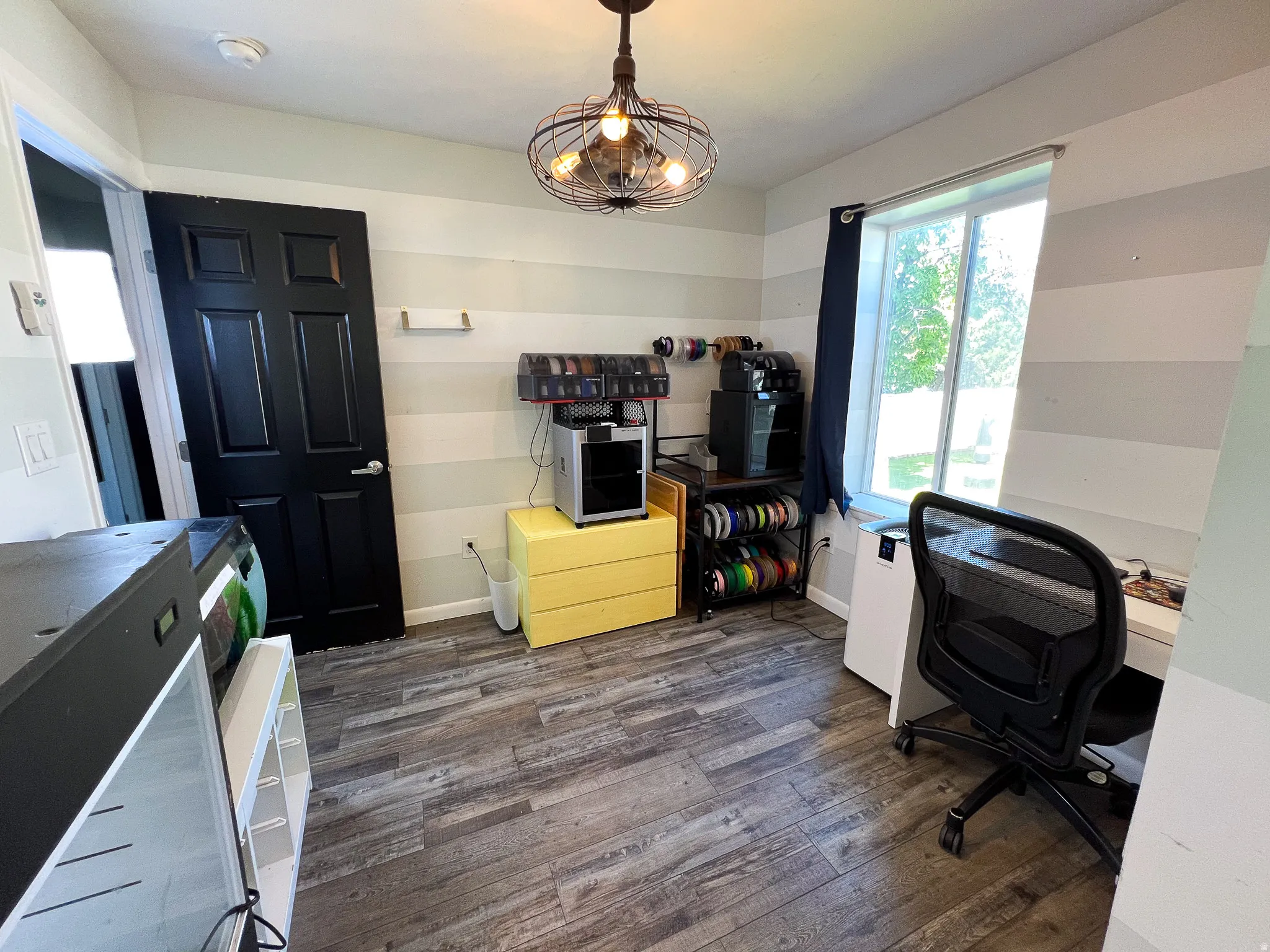 Room with wood-finish flooring, a contemporary ceiling light fixture, and 2 large window