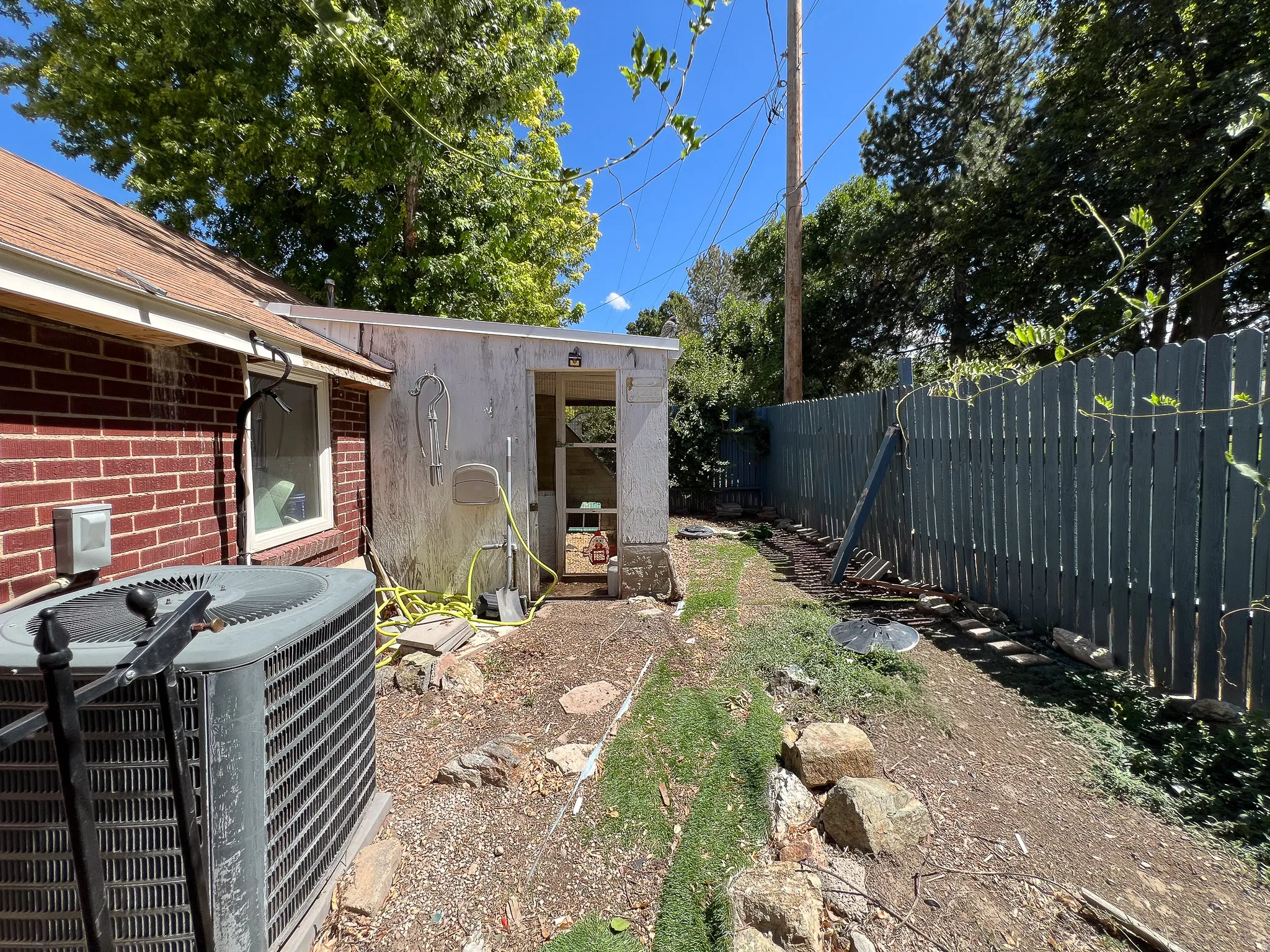 Brick exterior with a peaked roof, fenced yard, and a detached garage and chicken coop