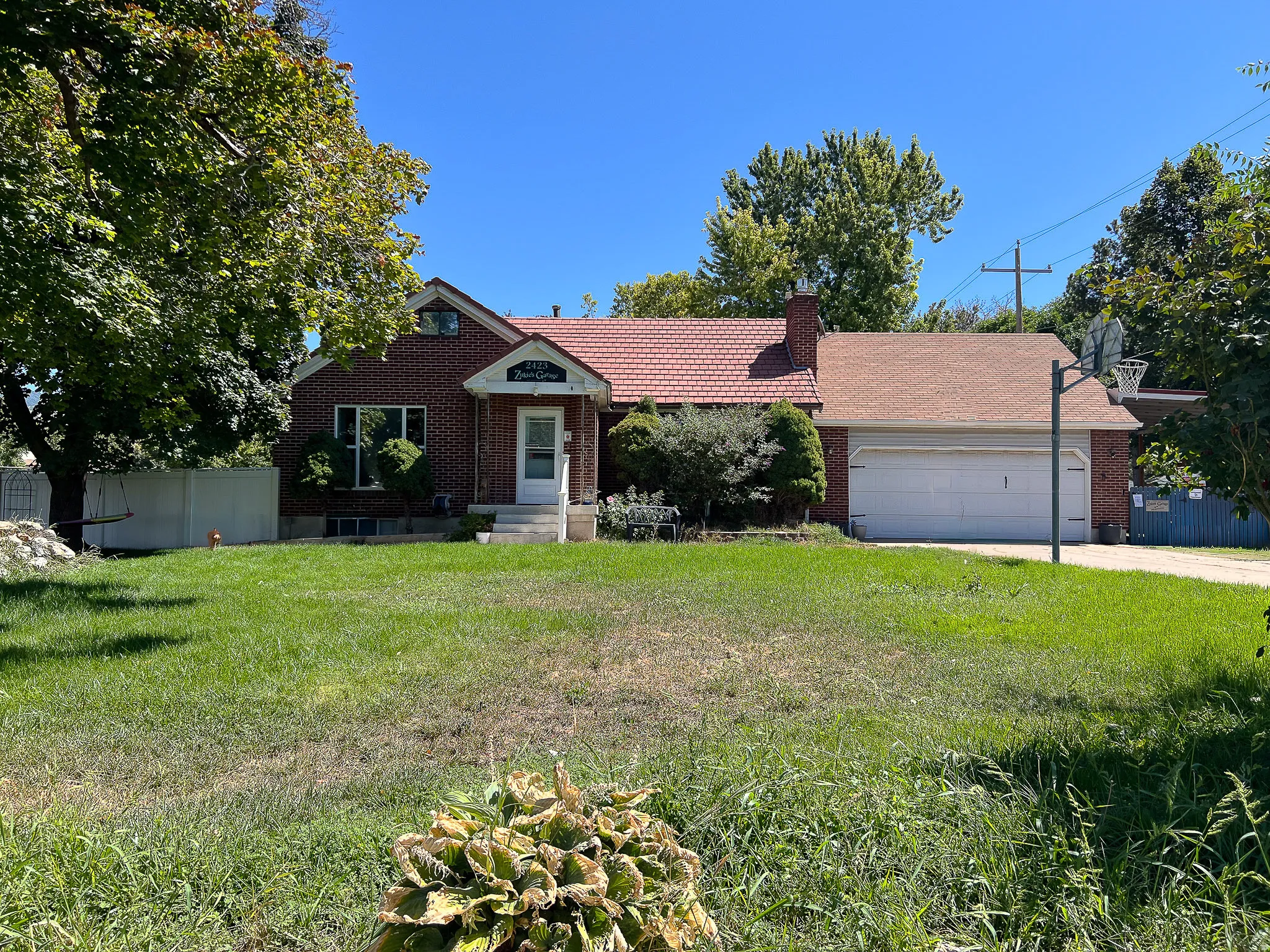 Red brick exterior with a tiled main roof and an asphalt shingle garage roof