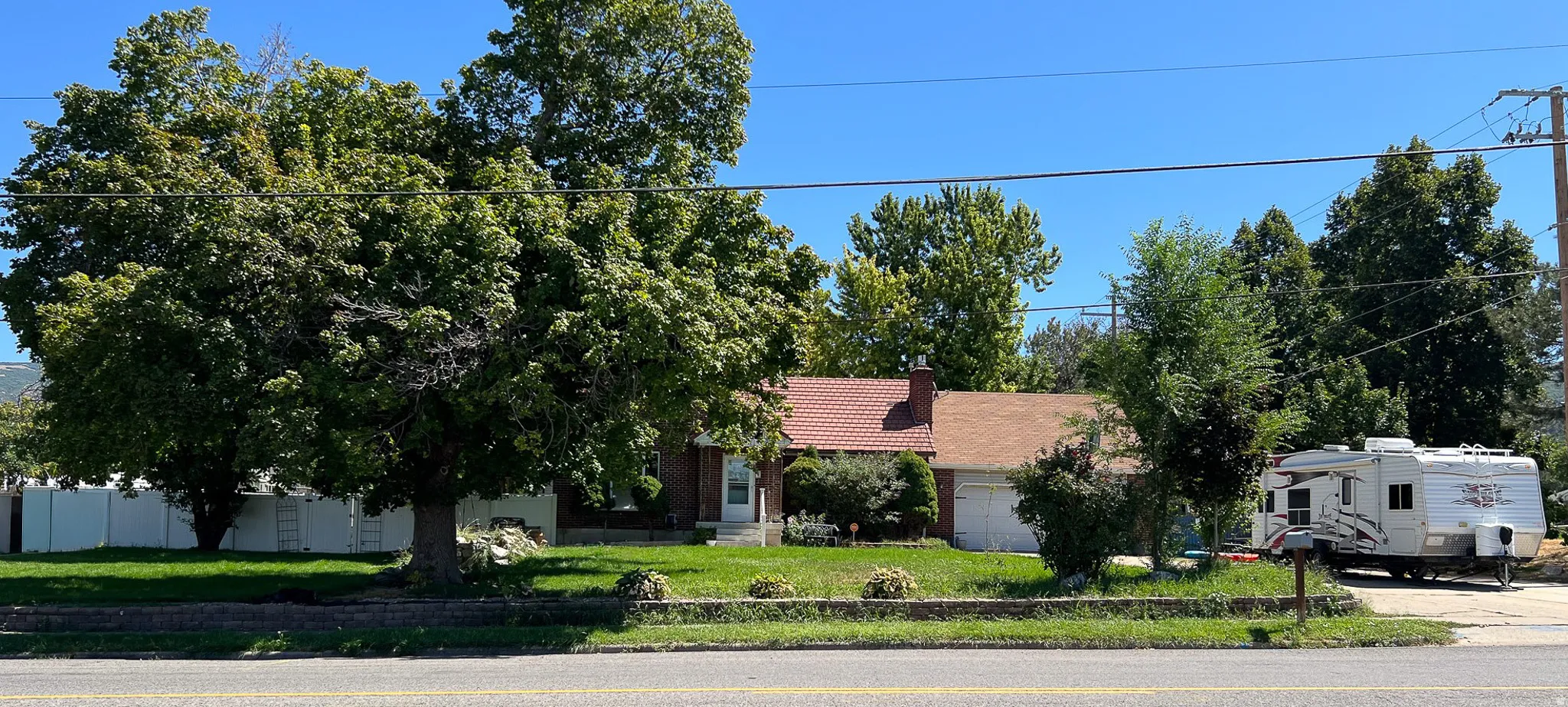 Brick exterior with a red-shingled roof and an attached two-car garage and detached garage