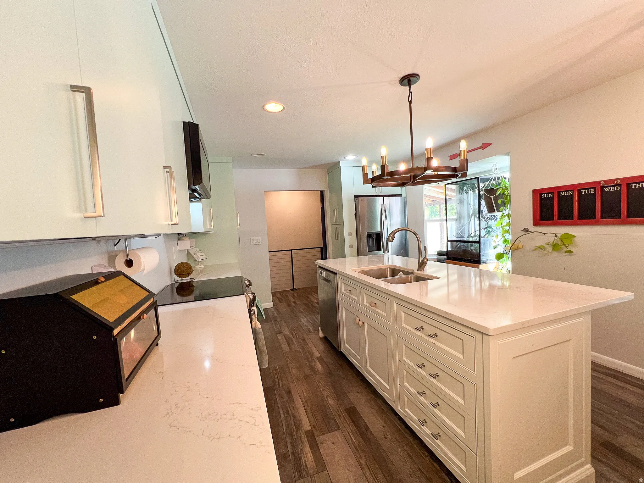 Kitchen featuring a center island with integrated sink, white cabinetry, dark wood-finish flooring, and recessed lighting