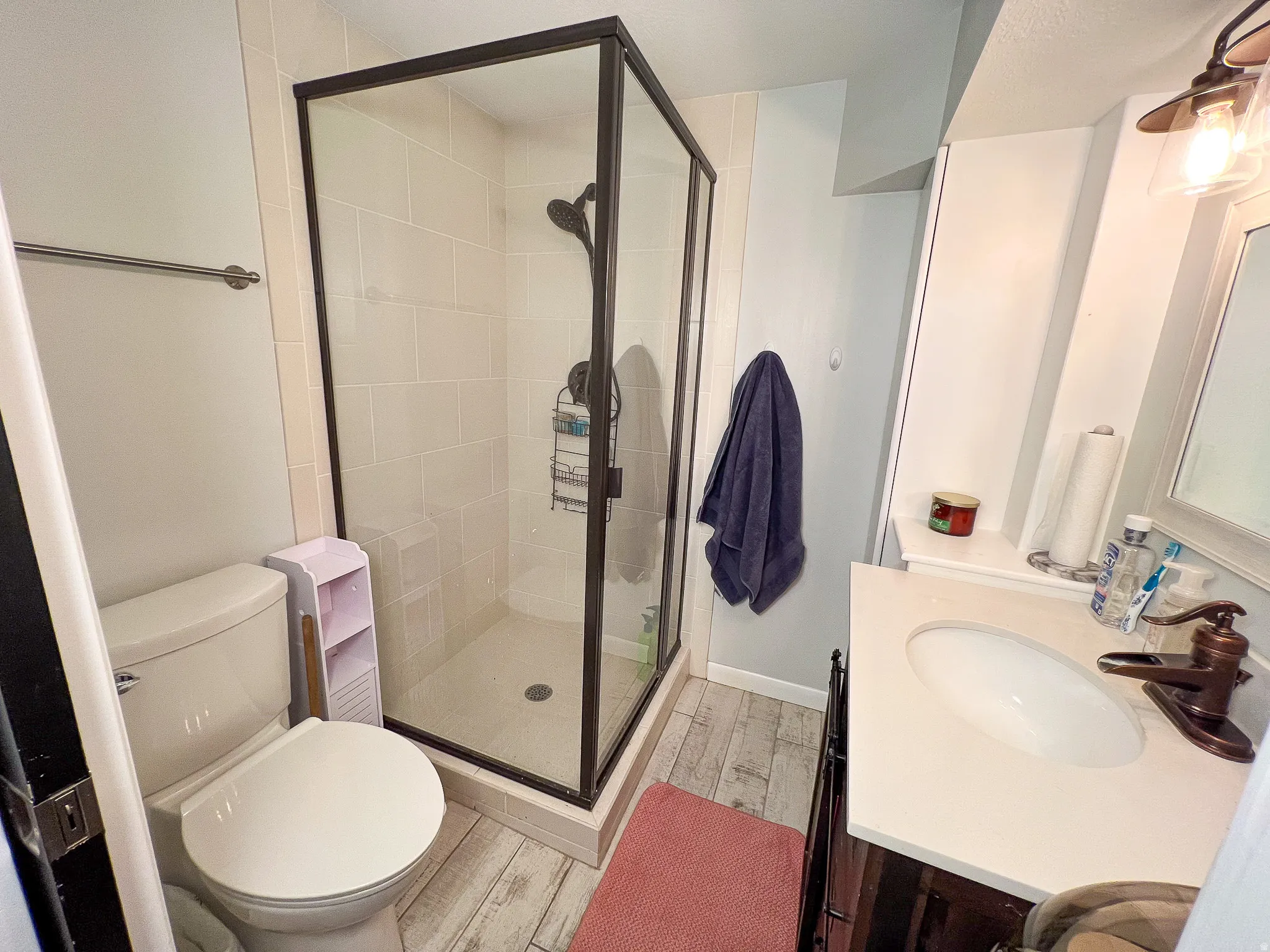 Glass-enclosed shower with dark bronze framing, light-toned shower tile, and a dark bronze shower fixture