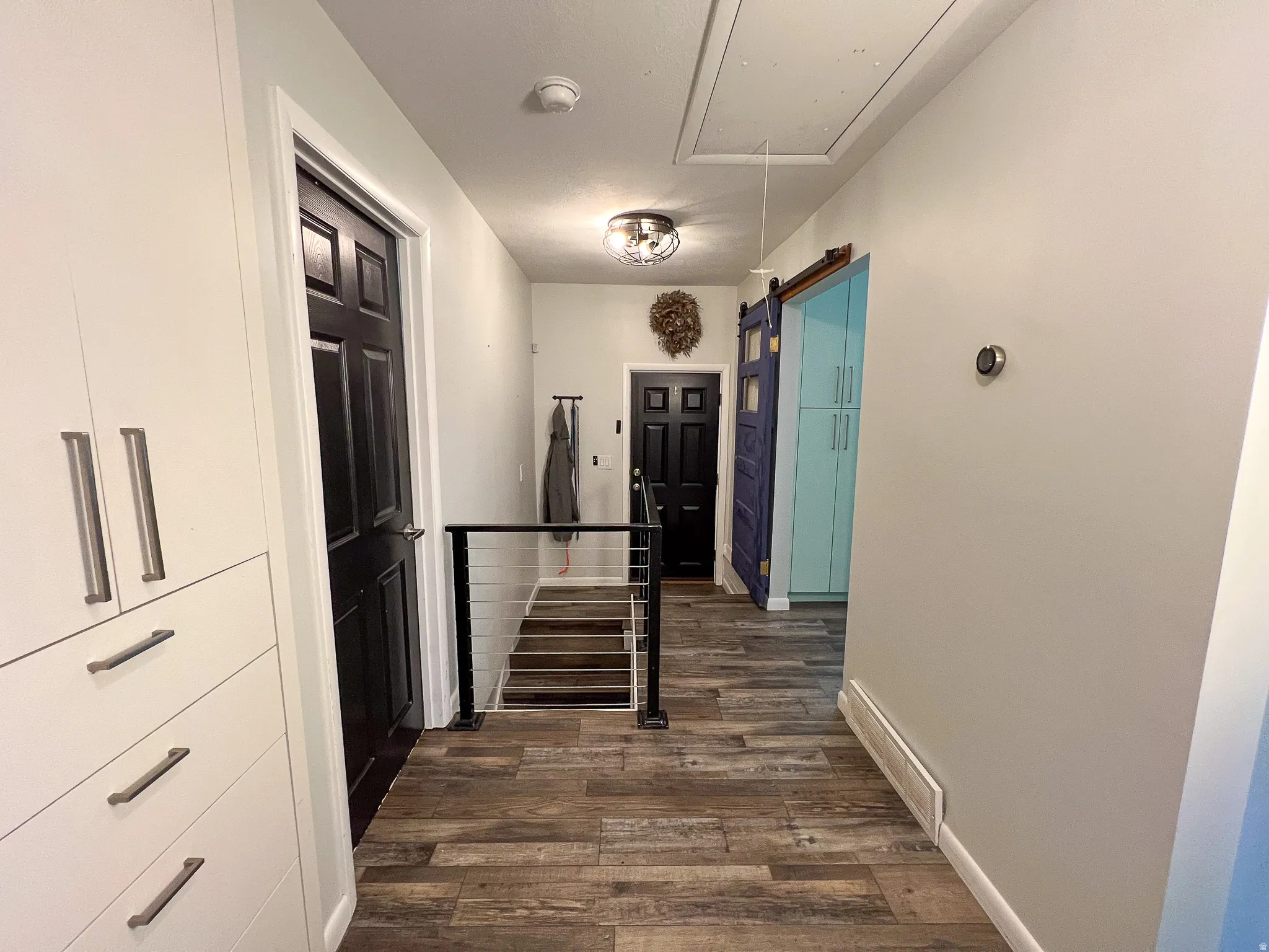 Wood-finish flooring throughout, with a cable railing system, built-in cabinetry, and a sliding barn door