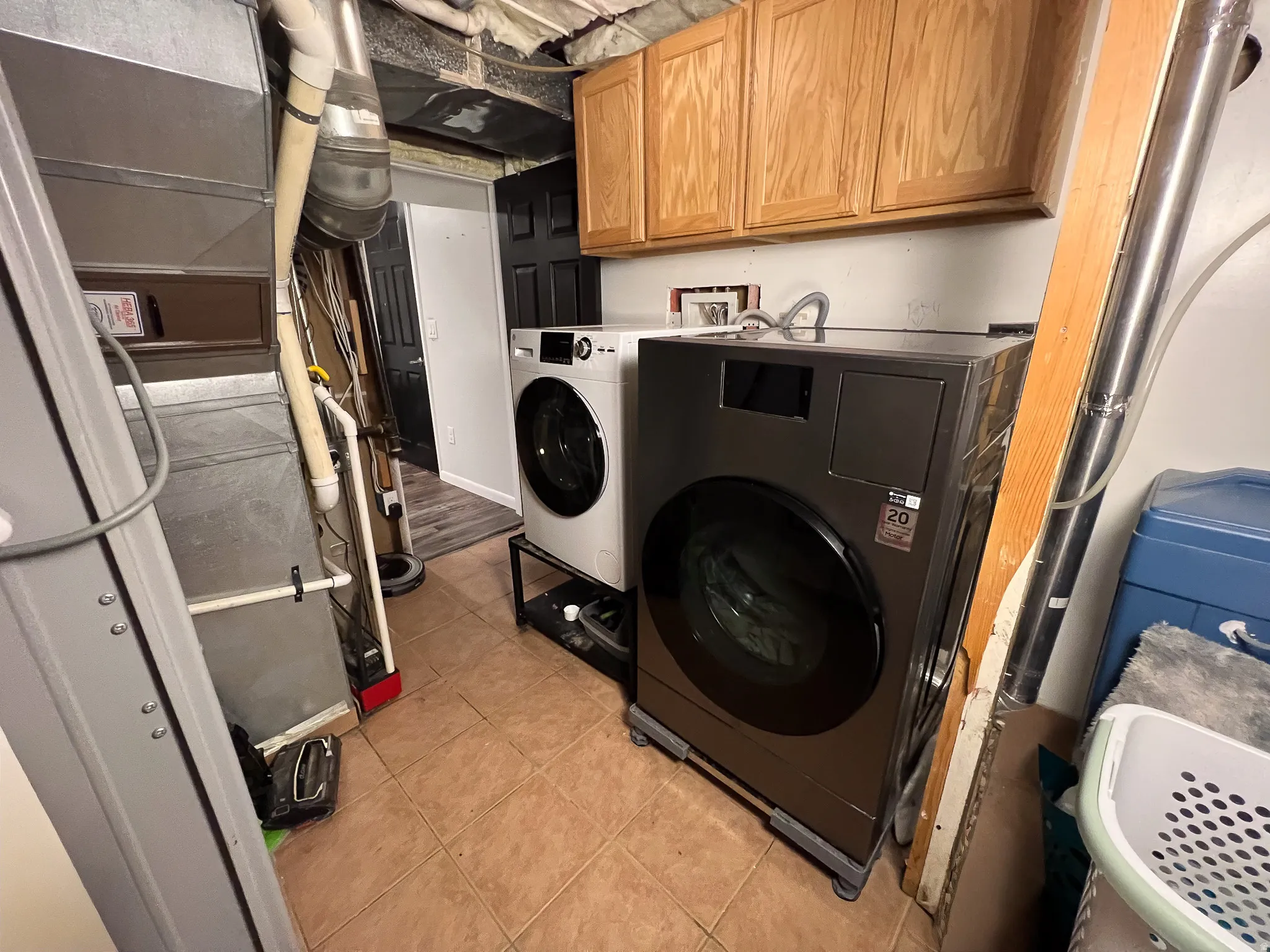 Utility area featuring durable tile flooring and wood-finish cabinetry