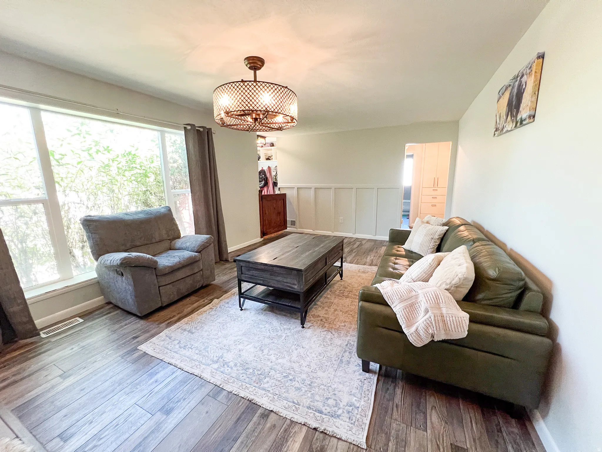 Spacious room featuring wood-finish flooring, large windows, and a decorative ceiling light fixture