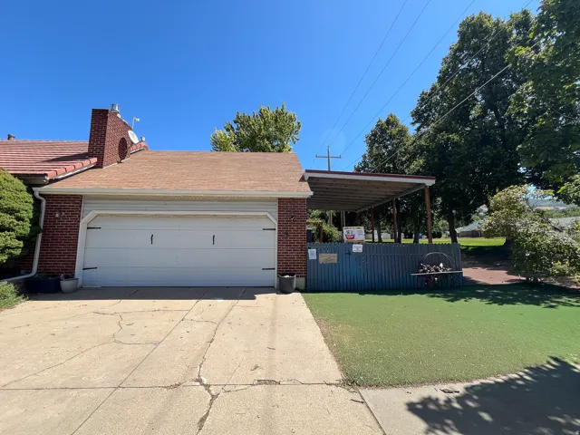 Brick facade with an attached garage and detached Garage, a covered outdoor structure, and a concrete driveway