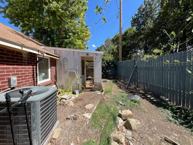 Brick exterior with a peaked roof, fenced yard, and a detached garage and chicken coop