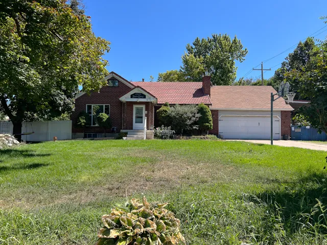 Red brick exterior with a tiled main roof and an asphalt shingle garage roof