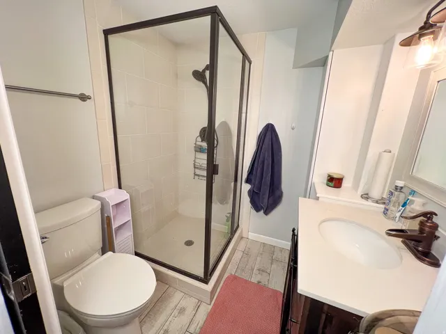 Glass-enclosed shower with dark bronze framing, light-toned shower tile, and a dark bronze shower fixture