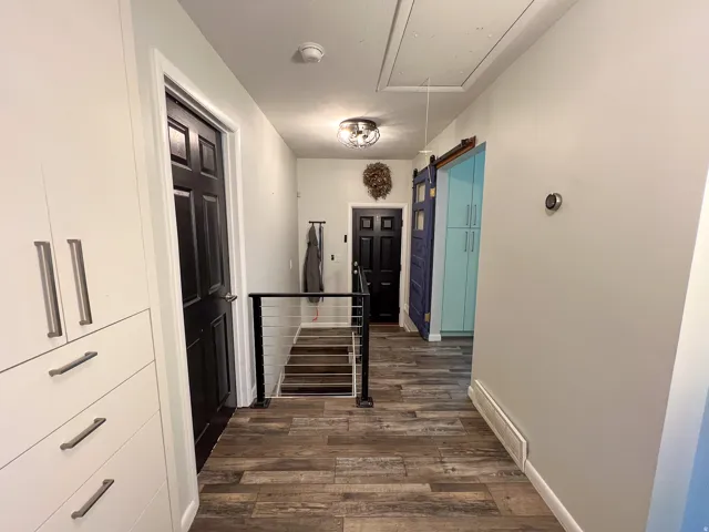 Wood-finish flooring throughout, with a cable railing system, built-in cabinetry, and a sliding barn door