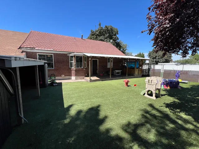Brick exterior with a red tile roof, covered patio, artificial turf, and a detached garage