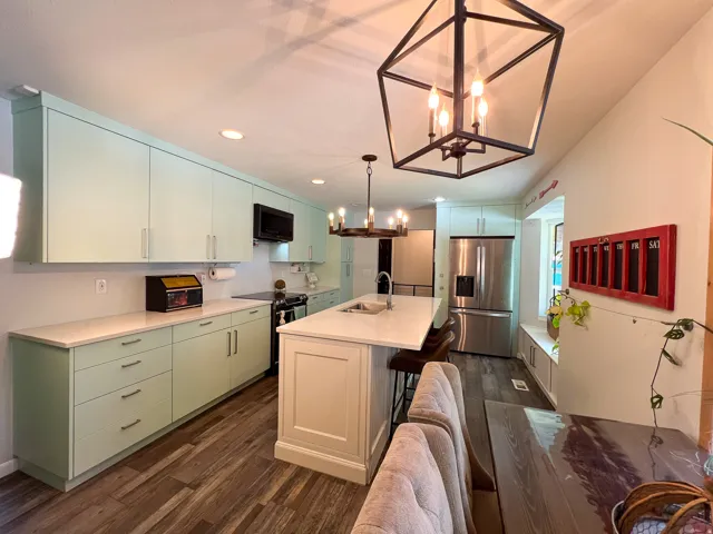 Kitchen featuring a central island, light-toned cabinetry, stainless steel appliances, wood-finish flooring, and a window seat with storage