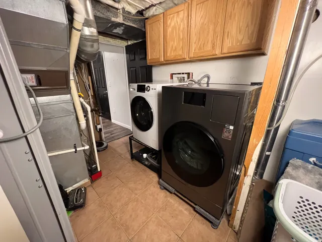 Utility area featuring durable tile flooring and wood-finish cabinetry