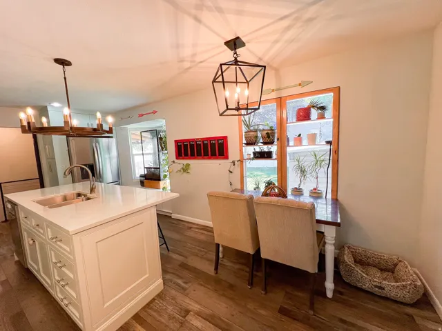 Kitchen island with integrated sink, white Quartz  countertop, wood-finish flooring, and recessed lighting