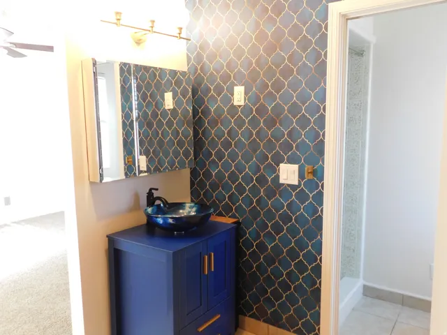 Vanity with a vessel sink, a mirrored medicine cabinet, and patterned wall covering