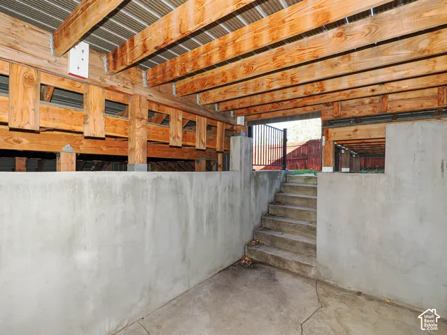 Concrete foundation walls with exposed timber joist ceiling and poured concrete staircase featuring metal handrails