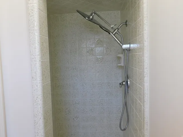Shower enclosure with light-toned wall tile and a dual shower head system