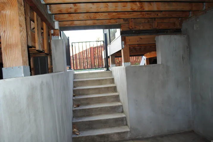 Concrete foundation walls with exposed wood structural beams and concrete stairs