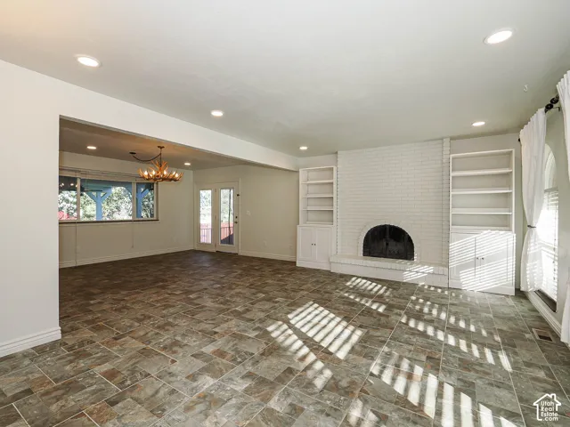 Multi-tone tile flooring, white-painted brick fireplace with a rounded hearth, recessed ceiling lighting, and  floor-to-ceiling cabinetry